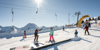 Kids and adults skiing in the sunny Funslope with wave course in Grossarltal ski area | © TVB Großarltal / Lorenz Masser
