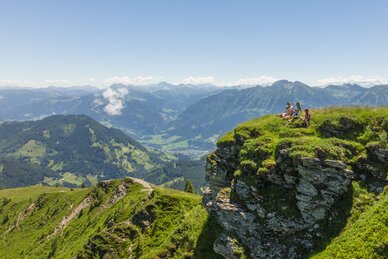Family sitting on a rocky outcrop with high mountains all around | © Roland Haschka