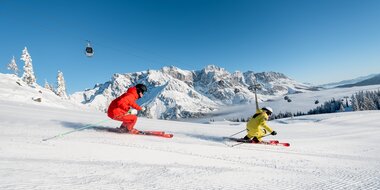 Two skiers on freshly groomed slope with view of the snowy Hochkönig mountain range | © Hochkönig Tourismus GmbH