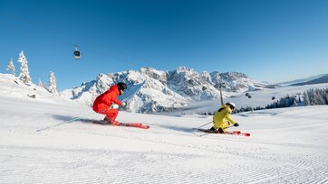 Two skiers on freshly groomed slope with view of the snowy Hochkönig mountain range | © Hochkönig Tourismus GmbH
