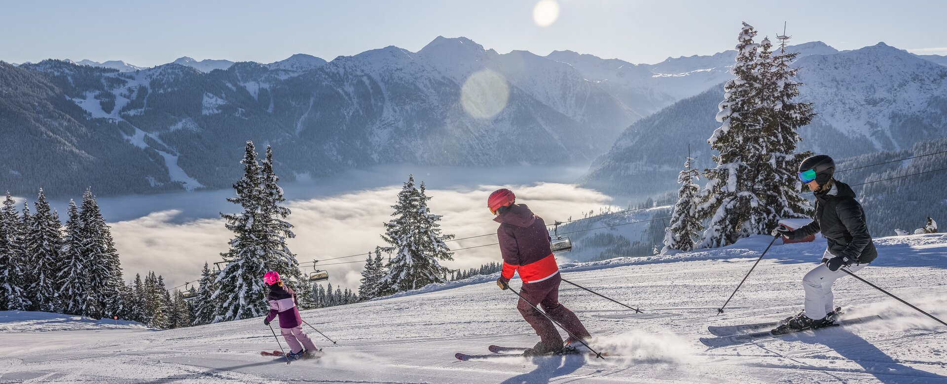 Eine Familie fährt die Piste mit Skiern hinab und rundherum ist alles schneebedeckt | © Salzburger_Sportwelt_Michael_Groessinger
