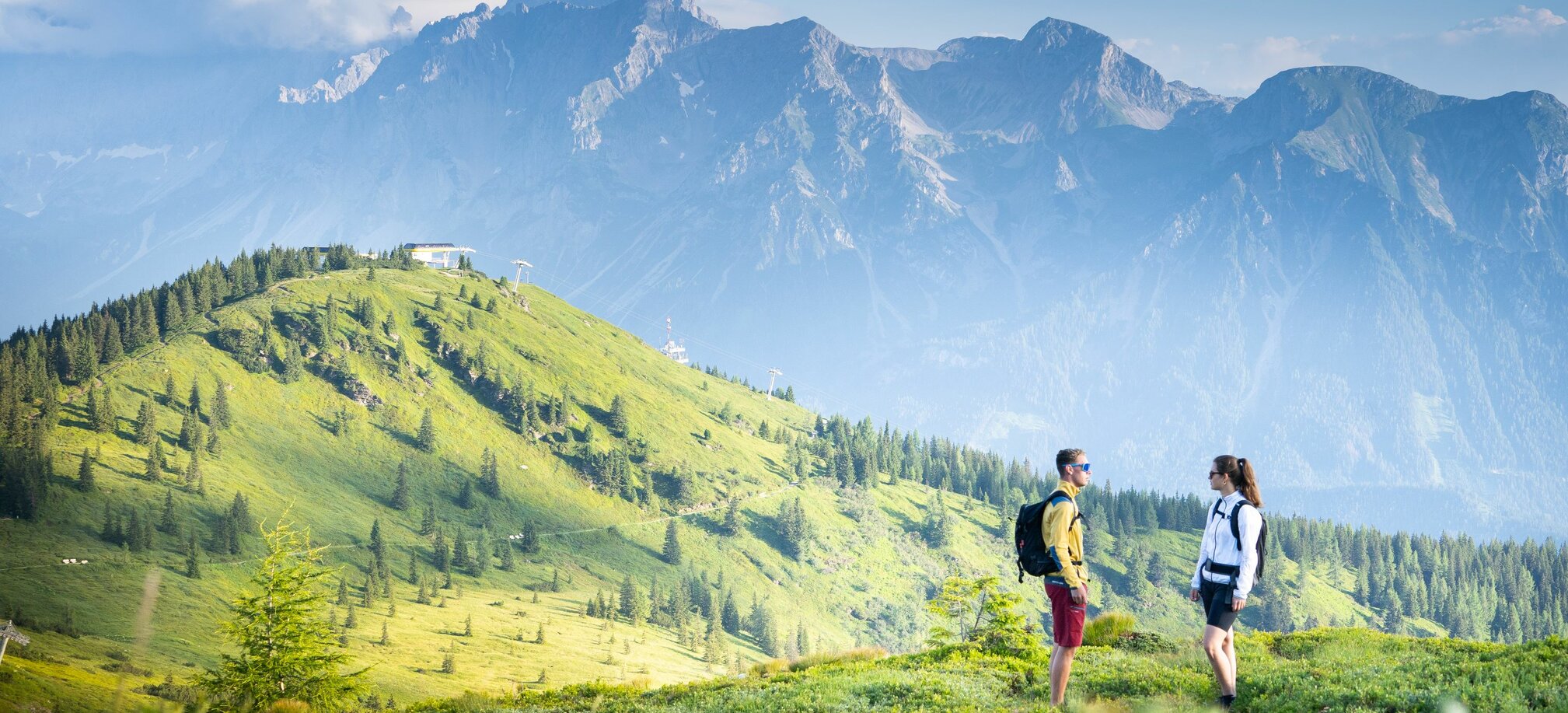 Two hikers stand on a meadow on the Planai | © Josh Absenger
