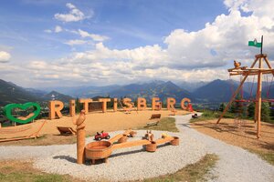 Panoramic playground with wooden letters, swings and water play set against mountains on Rittisberg | © Photo Austria, Hans-Peter Steiner