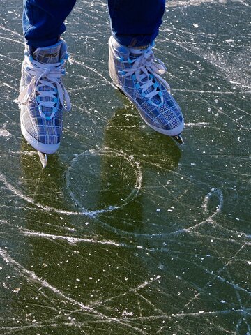 Close-up of ice skates on scratched surface of a frozen natural lake | © Pixabay