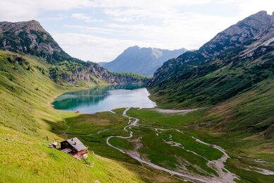 View of a clear alpine lake with hut, meadows and streams in a high valley surrounded by mountains | © Wagrain-Kleinarl Tourismus