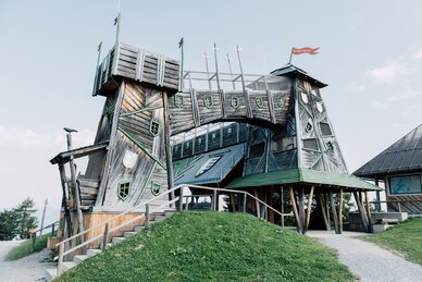 Verwinkeltes Holzschloss mit Türmen und Brücke im Freizeitpark Geisterberg, märchenhaft gestaltet mit vielen grünen Fenstern