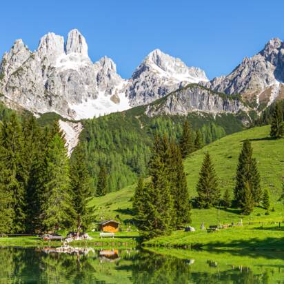Crystal-clear Almsee reflecting the Bischofsmütze mountain, green meadow and forest in summer near Filzmoos, Austria | © CoenWeesjes
