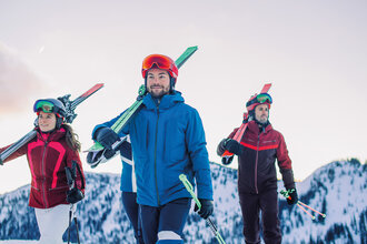 Vier Skifahrer tragen ihre Ski auf der Schulter – idealer Start für den Skikurs Back2Ski, ein Kurs für Wiedereinsteiger. | © Ski amadé