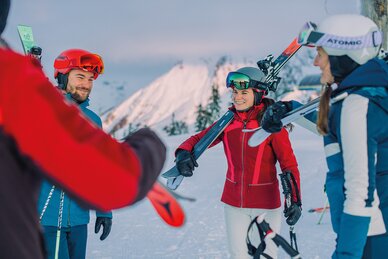 A group of skiers carrying their skis chats together – part of the Back2Ski course for returning skiers. | © Ski amadé